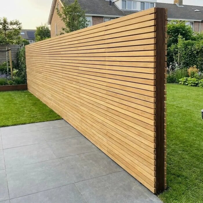 Free standing double sided teak fence between patio and lawn, with only the Azobe end post showing between the two layers of slats Free standing double sided teak fence between patio and lawn, with only the Azobe end post showing between the two layers of slats