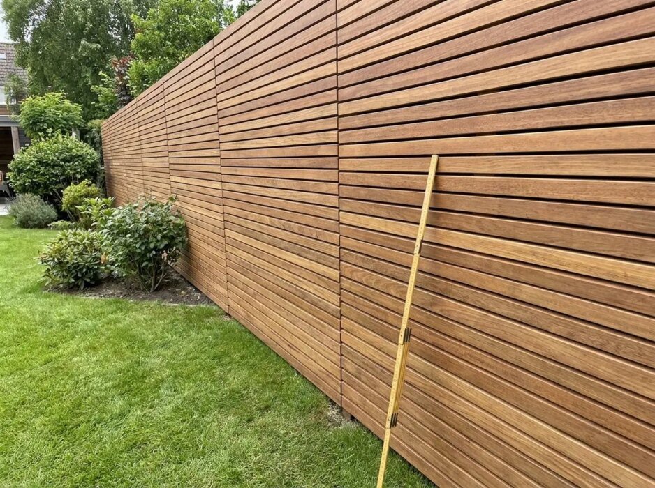 Ipe fence with horizontal 50 mm slats and a folding rule leaning against them Ipe fence with horizontal 50 mm slats and a folding rule leaning against them