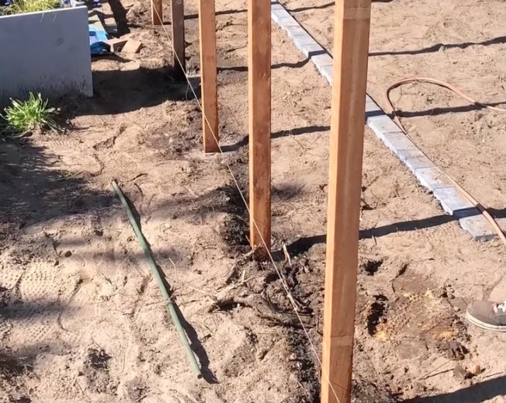 Installation of Azobe hardwood fence posts Installing durable Azobe hardwood fence posts precisely aligned along a cord in the ground