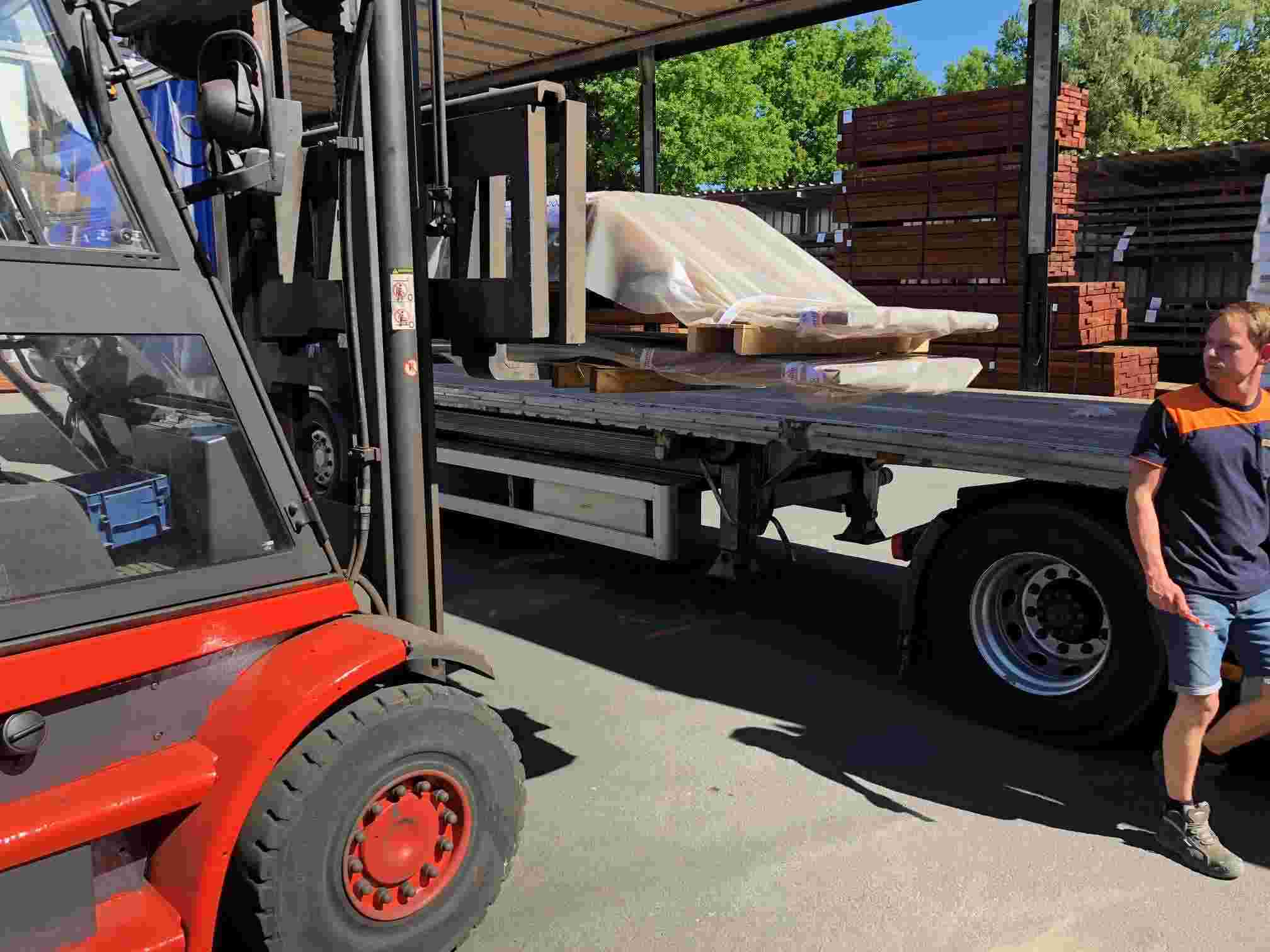 A forklift truck carefully moves stacked hardwood bundles inside the storage hall