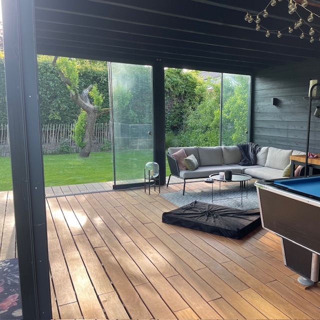 Spacious modern black garden house with glass doors opening onto a luxury Ipe hardwood terrace