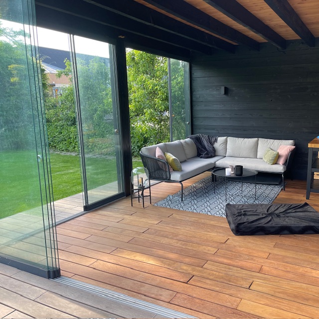 Contemporary black garden house designed with glass sliding walls and a durable Ipe timber deck