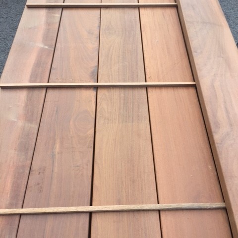 Long smooth planed Ipe hardwood timber beams stacked with wooden spacers in storage