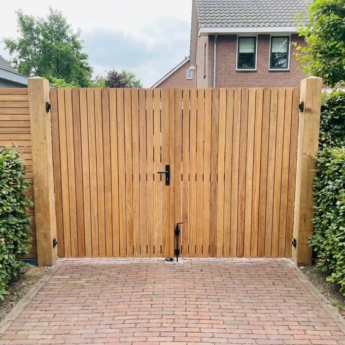 Double teak garden gate at the end of a drive