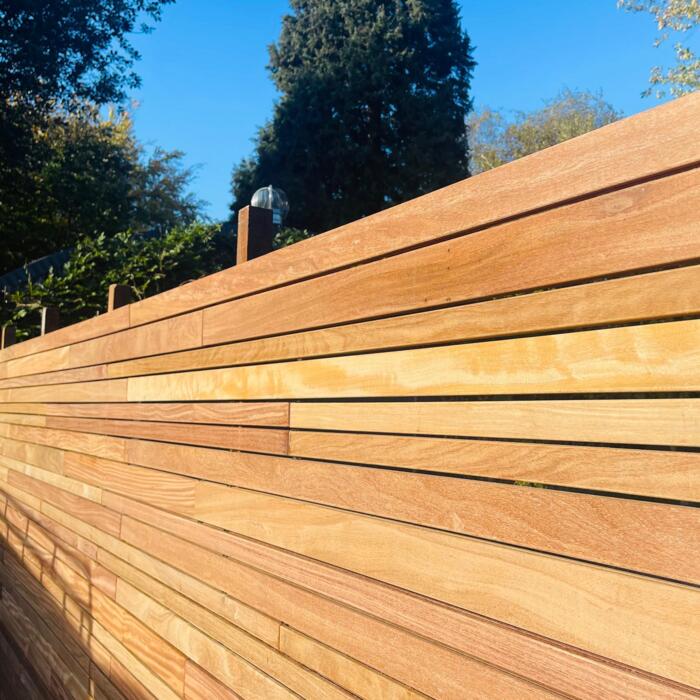 Luxury Ipé hardwood variation fence with 5, 7 and 9 cm wide slats in a trendy garden.