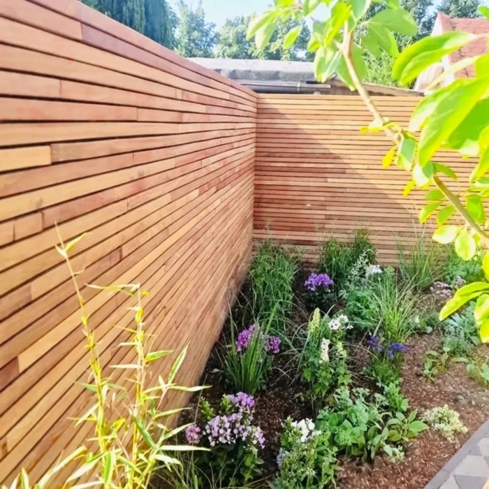 Teak fence with 50 mm slats in a garden corner with a border