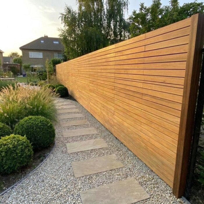Long run of teak fencing with 50 mm slats along a garden path, set dead straight