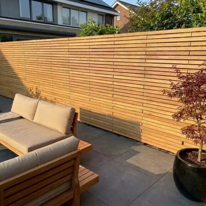 Teak slatted fence with 50 mm slats sheltering a lounge area Teak slatted fence with 50 mm slats sheltering a lounge area
