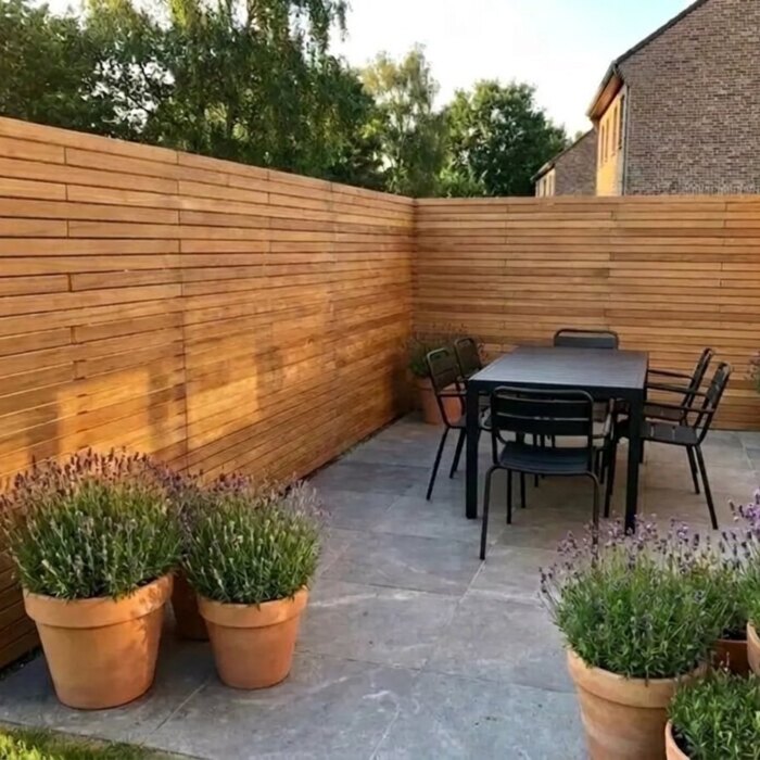 Wrapped round the patio: Teak fence with 7 cm slats around a patio corner with a dining table