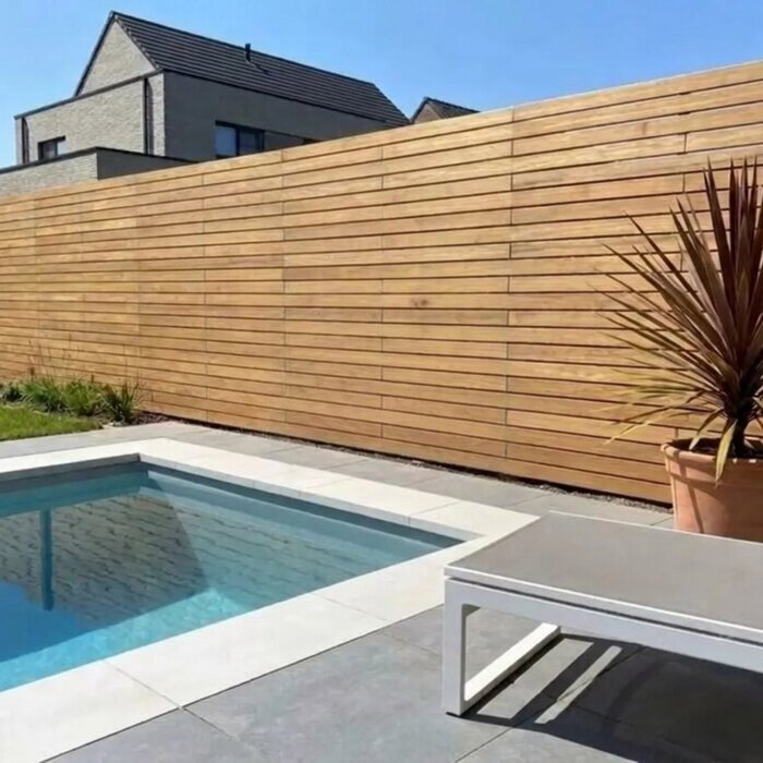 By the pool: Teak fence with 9 cm slats beside a swimming pool in a modern garden