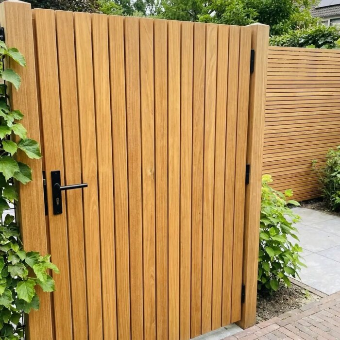 Teak garden gate with 50 mm slats next to a climbing hydrangea, with black lever handle