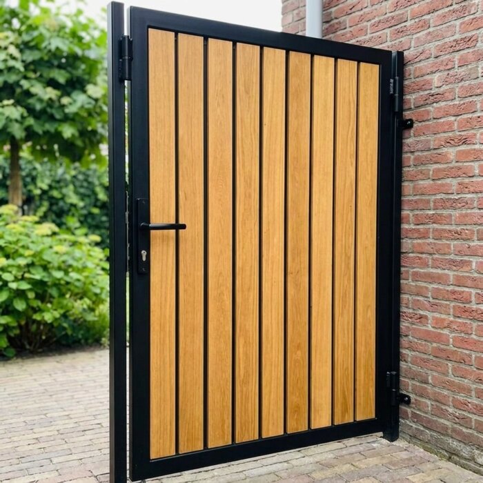 Black steel frame and hinge of a teak garden gate next to a heavy gate post Black steel frame and hinge of a teak garden gate next to a heavy gate post