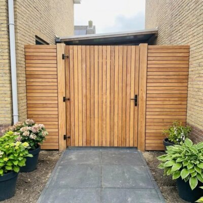 Teak garden gate with 50 mm slats in a side passage next to a yellow brick house