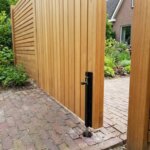 Close-up of the black drop bolt on the fixed leaf of the double teak gate