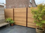 Teak fence with 9 cm slats in a courtyard garden with a Japanese maple