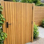 Teak garden gate with 50 mm slats next to a climbing hydrangea, with black lever handle