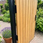 Close-up of the black hinge on the teak gate with 70 mm slats