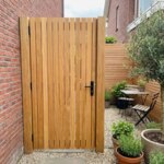 Teak gate with 90 mm slats in a courtyard garden with a brick wall and olive tree