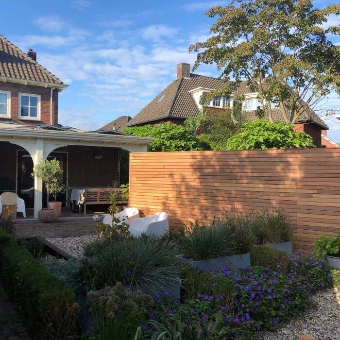 Atmospheric and sleek Ipe slatted timber fence in a compact urban garden, providing privacy and a contemporary luxury feel